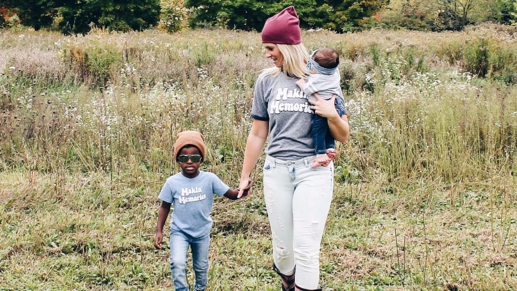 mom carrying a child and holding another childs hand