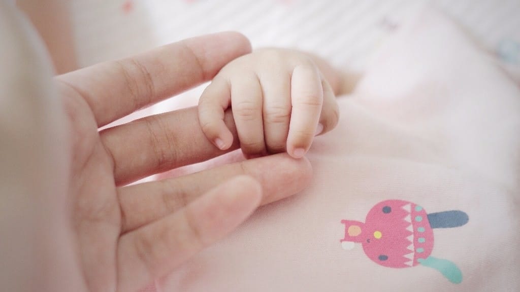 baby holding moms finger