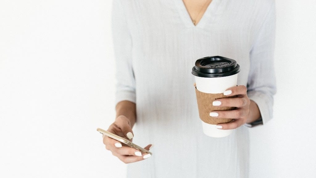 woman holding coffee and her phone