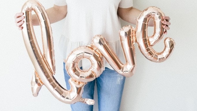 pregnant woman holding 'love' balloons