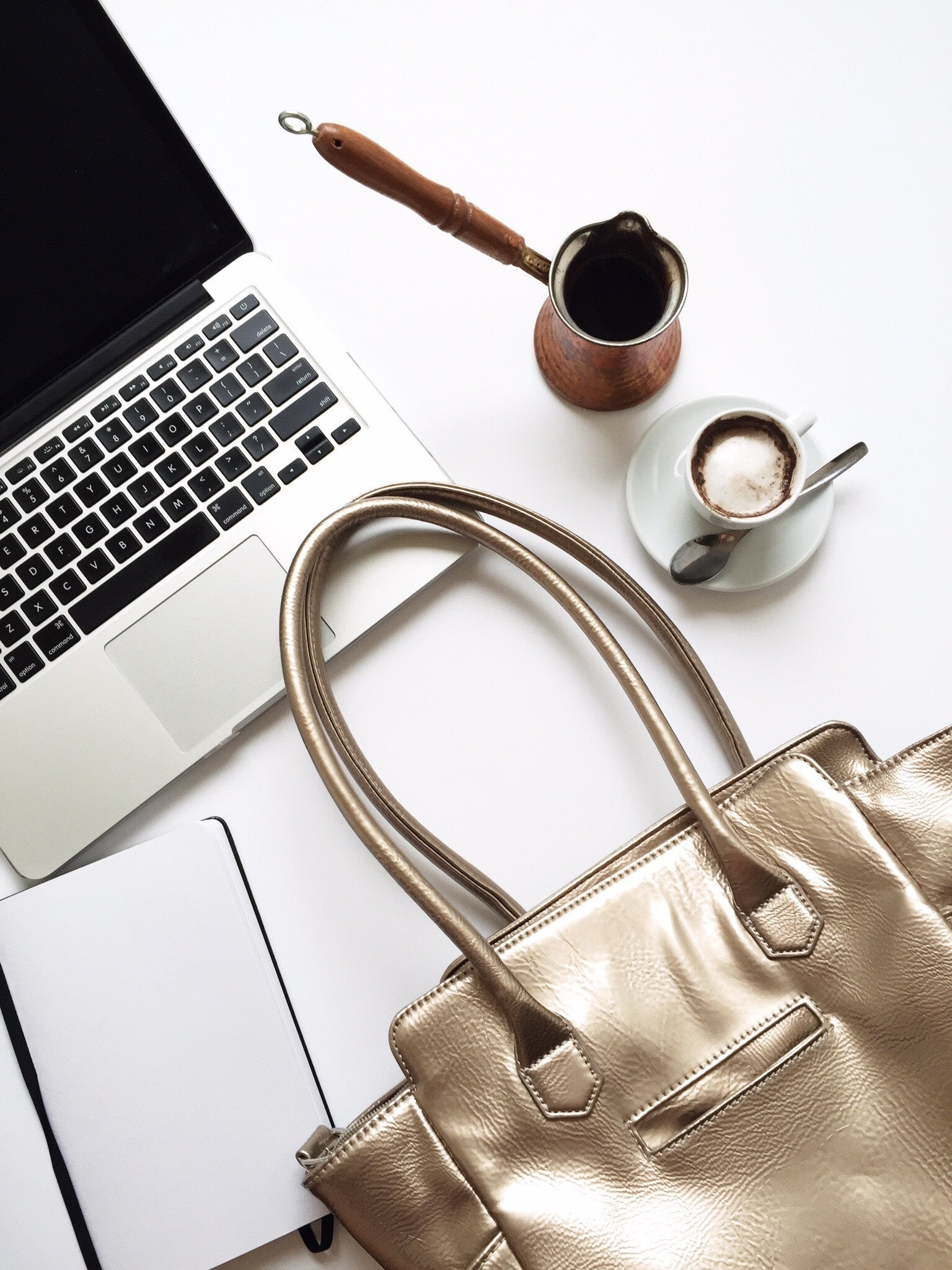 purse and coffee next to a laptop