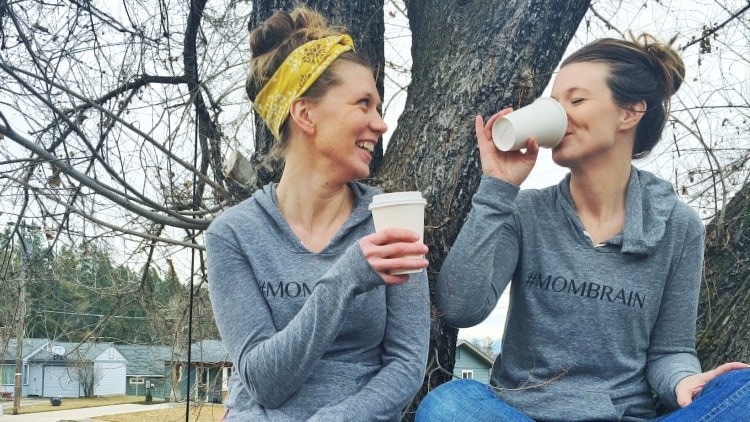 two moms drinking coffee together outside