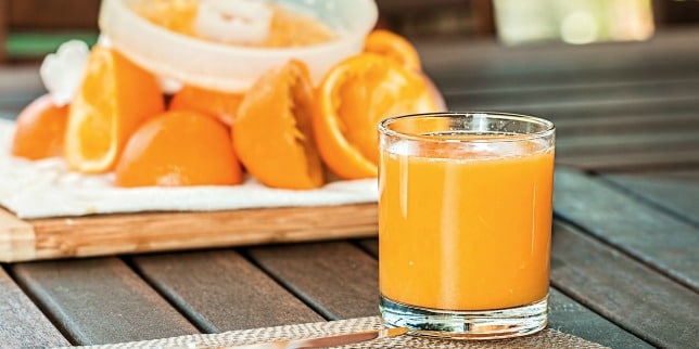 orange juice behind a bowl of oranges - juicing during pregnancy