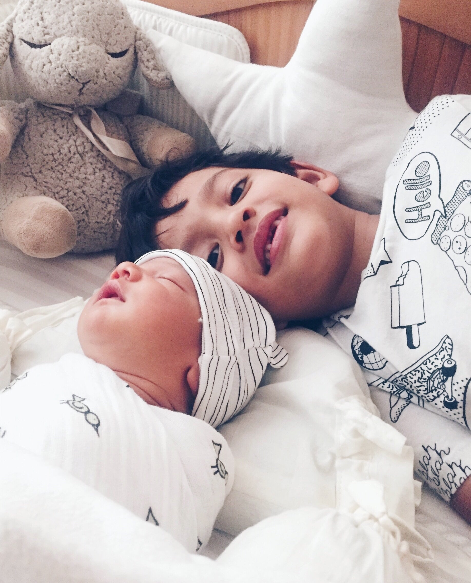 older sibling laying next to newborn sibling- new sibling transition