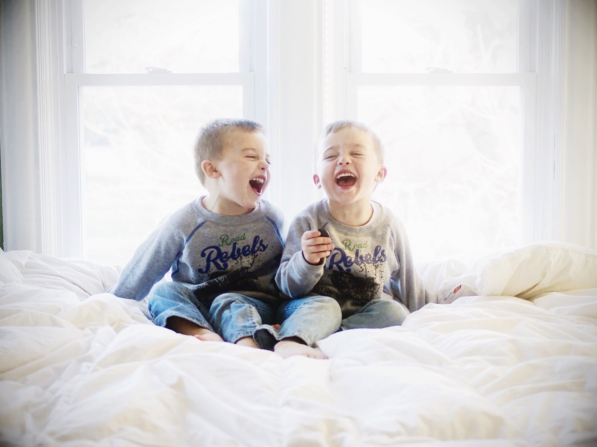 two boys laughing on a bed