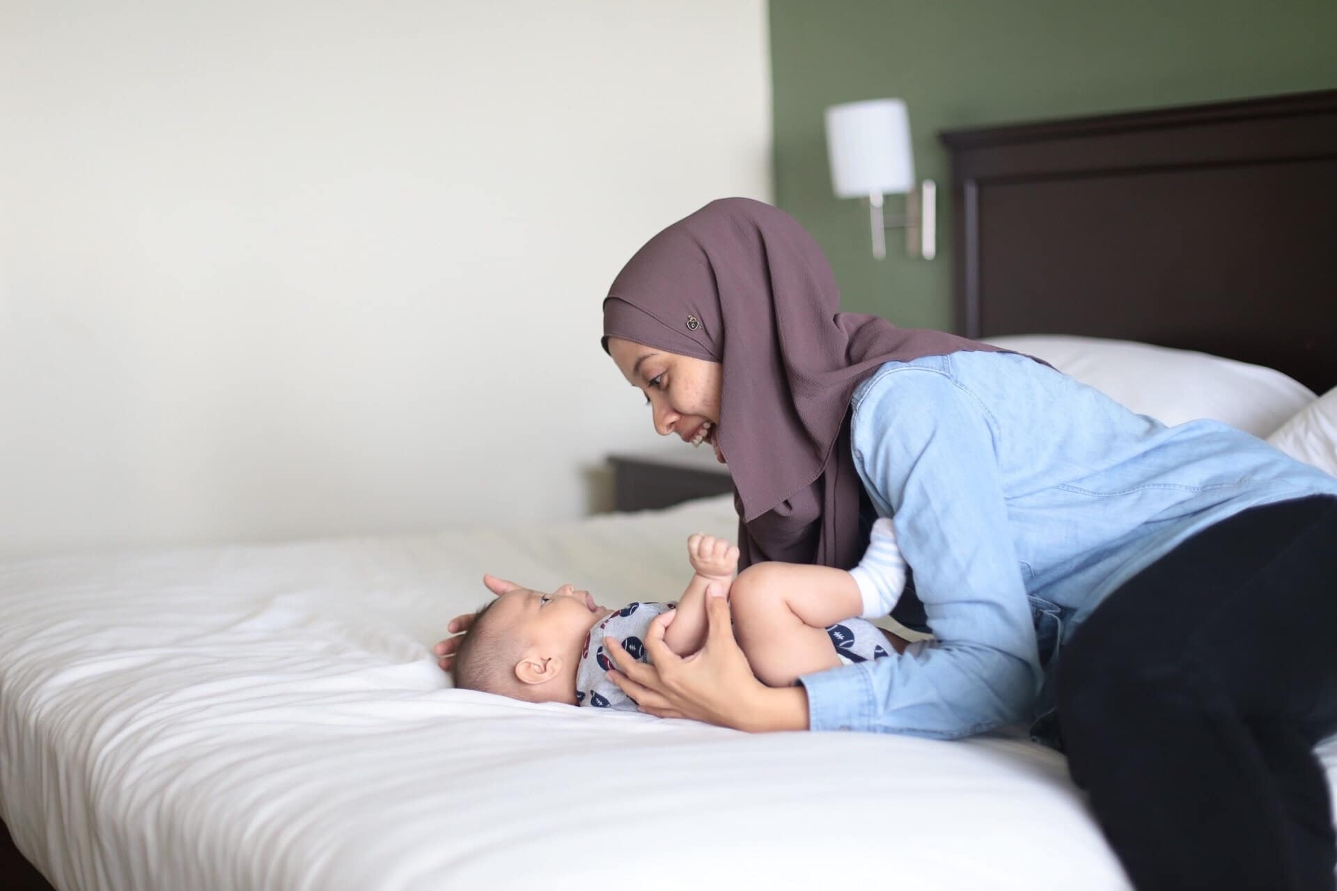 mom playing with baby on a bed