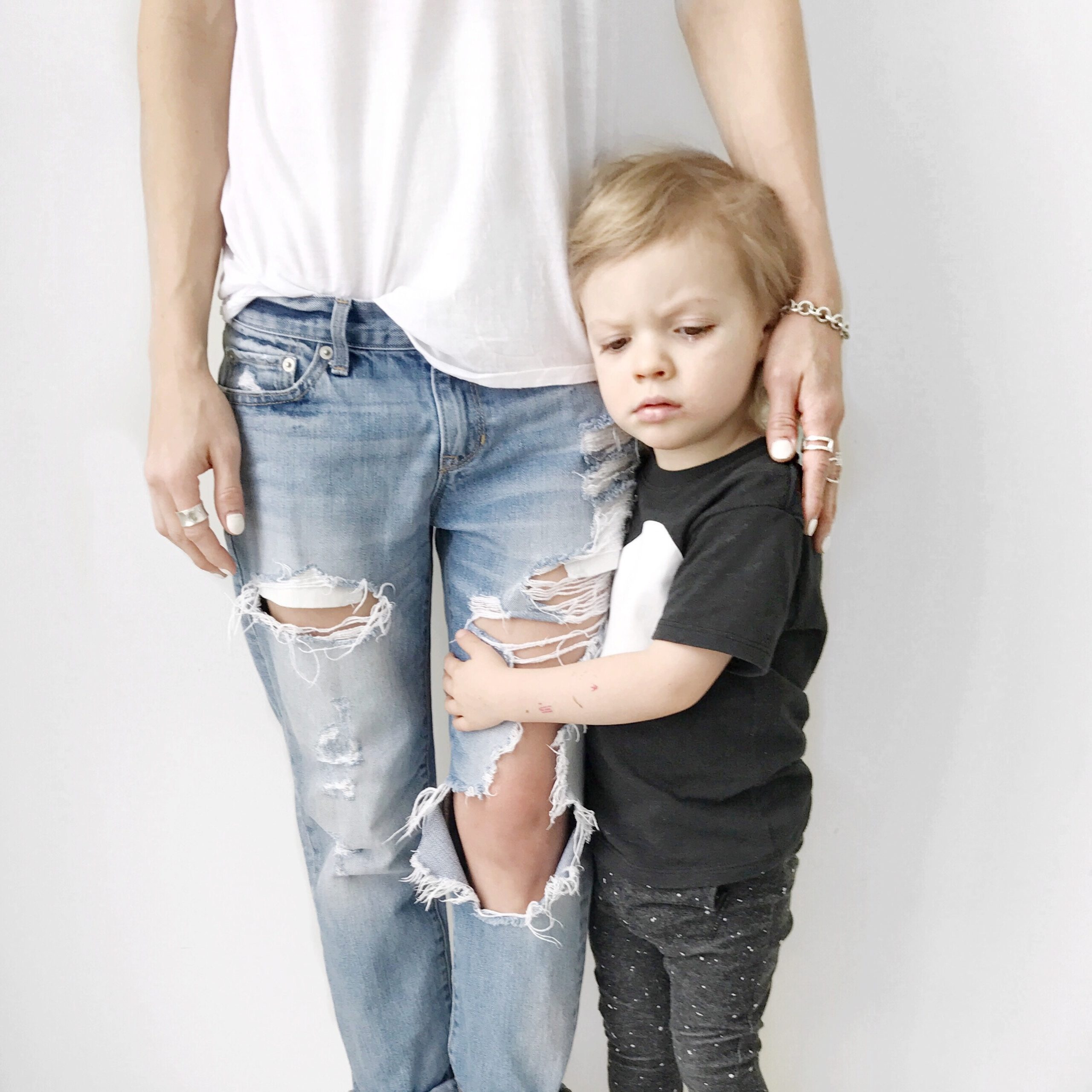 little boy hugging moms legs