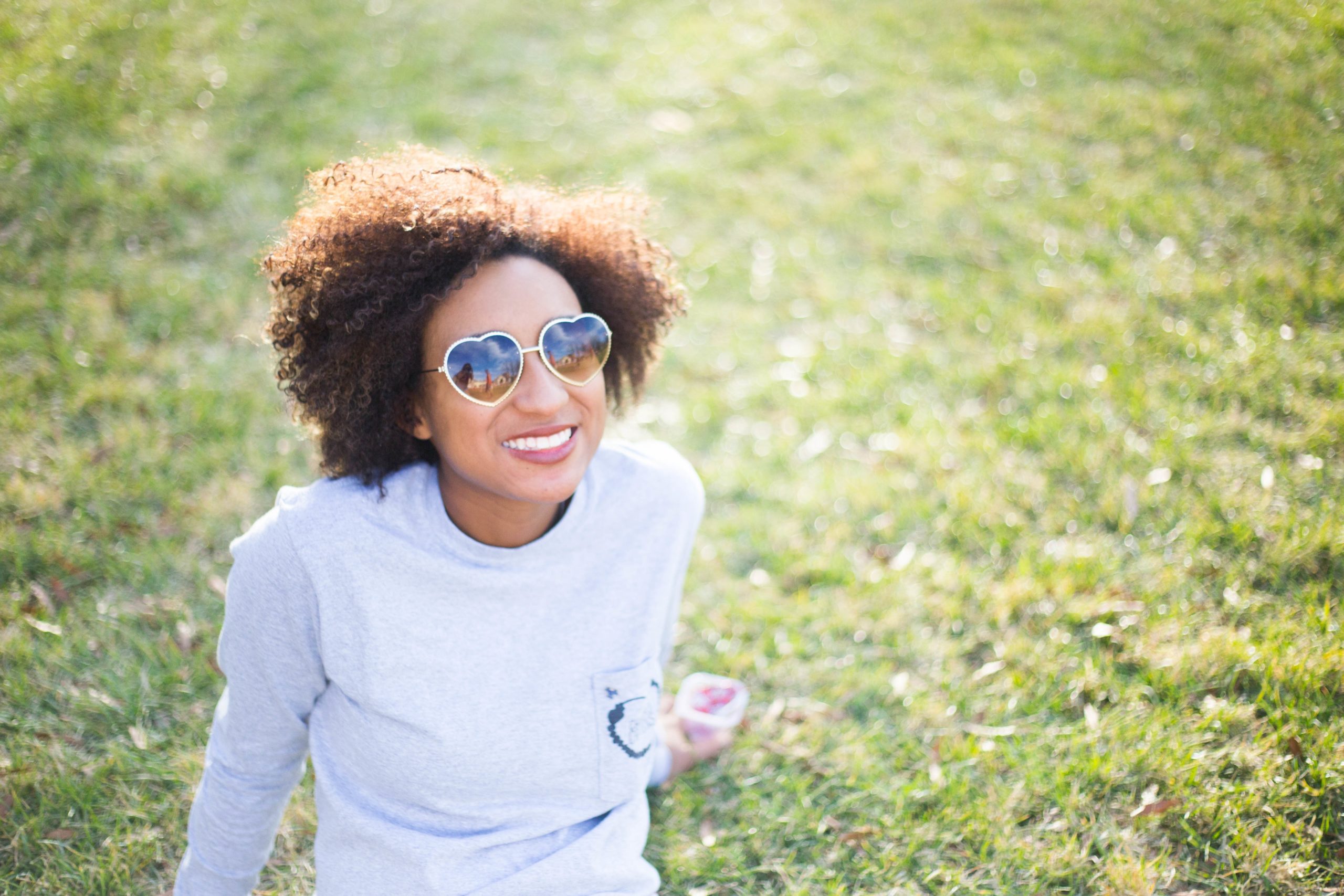 woman wearing heart sunglasses sitting on grass