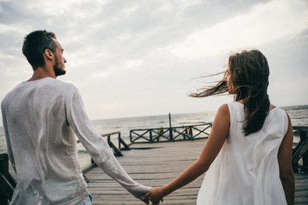 couple holding hands on a pier
