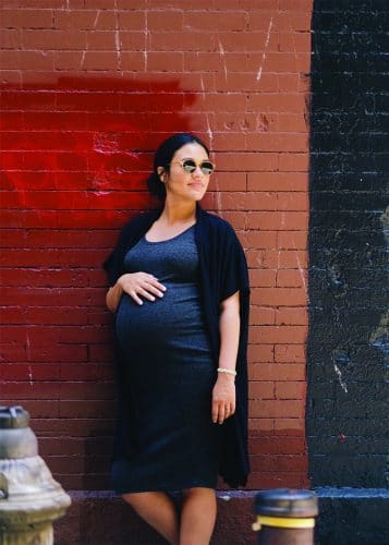 pregnant woman against brick wall with sunglasses