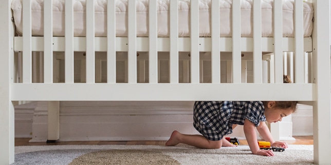 toddler crawling under a crib