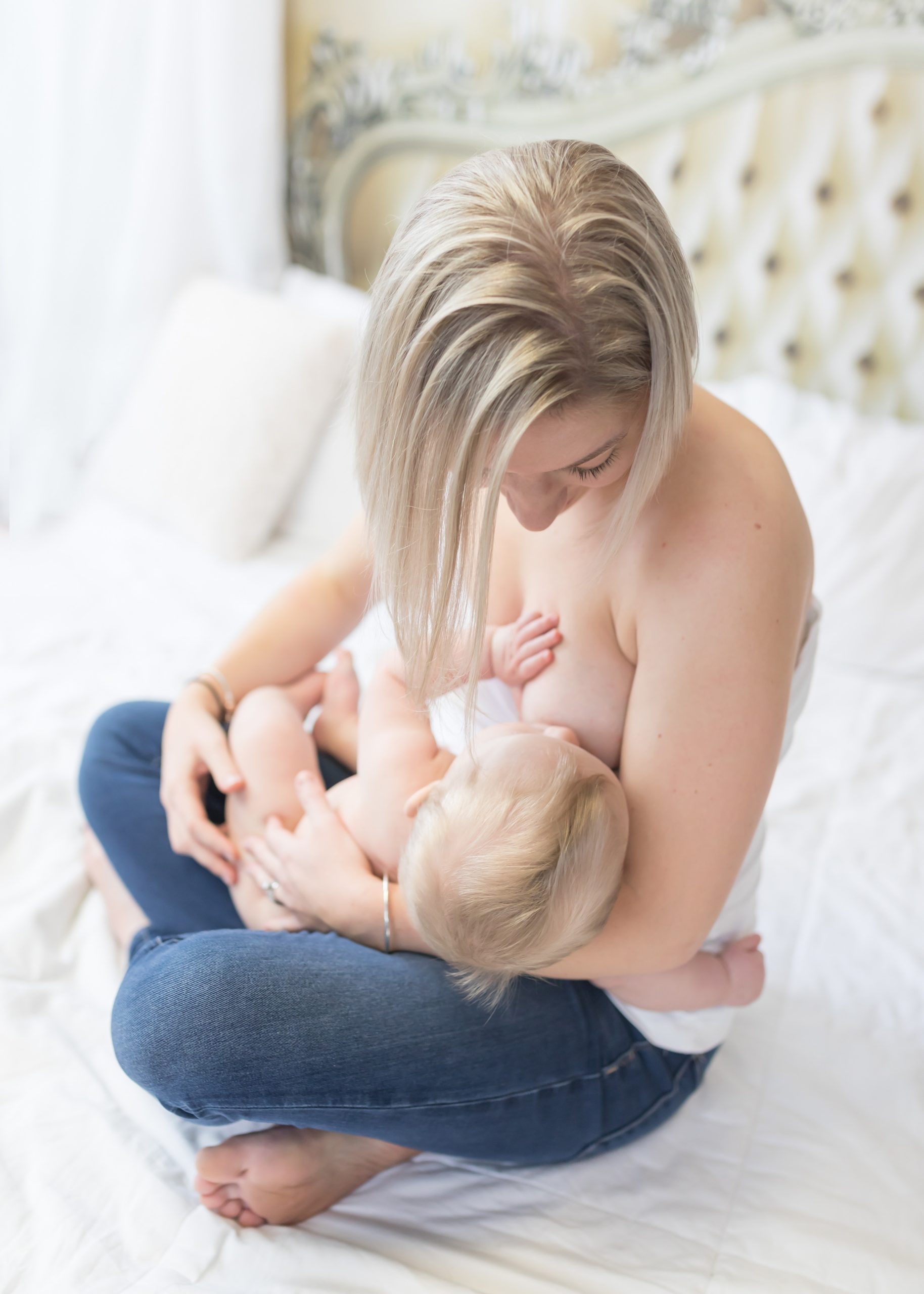 woman breastfeeding baby in a bed