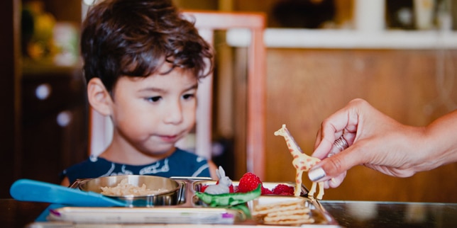 small boy playing with giraffe figurine