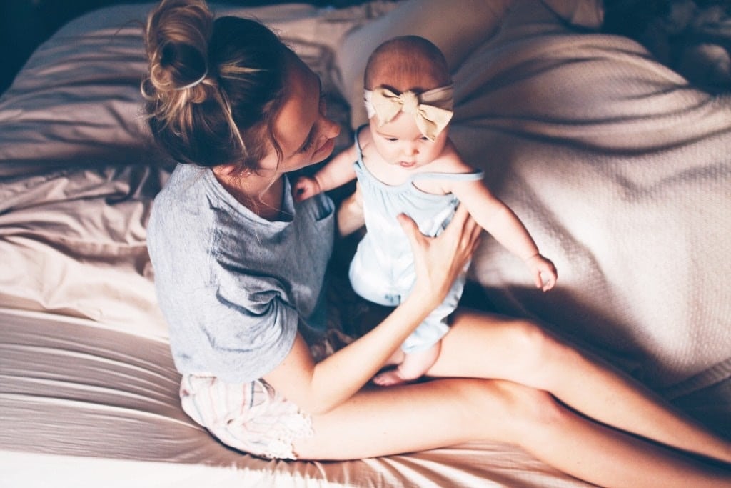 mom holding baby in bed