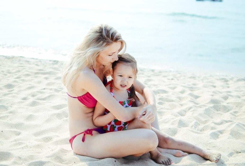 mom holding a toddler on a beach