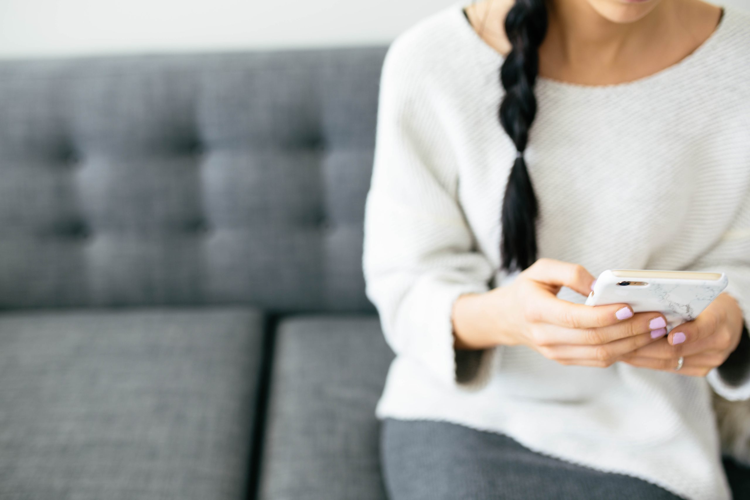woman sitting on the couch holding her phone - Motherly's MotherlyInsights Panel
