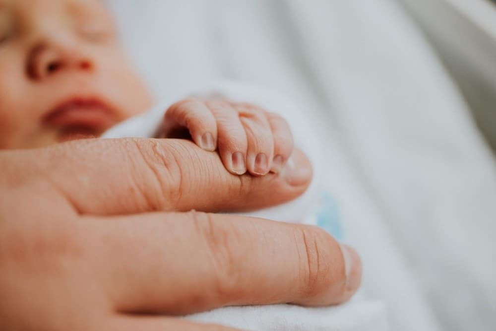 nicu baby clutching their mother's finger