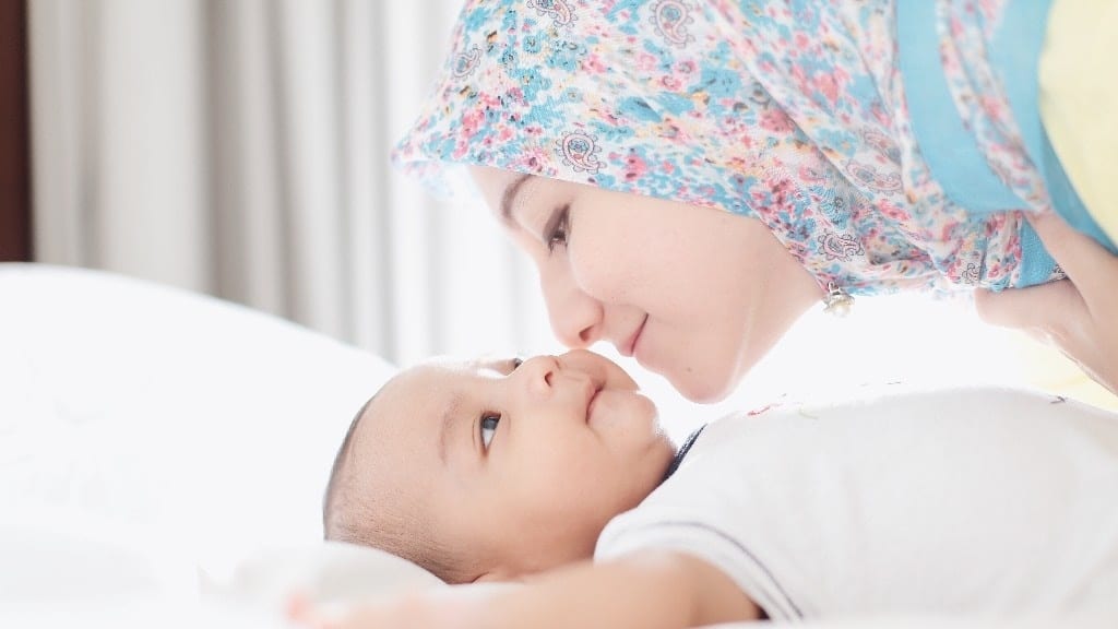 mom kissing newborn baby