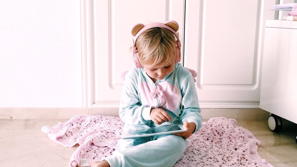 little girl sitting on bed with ipad