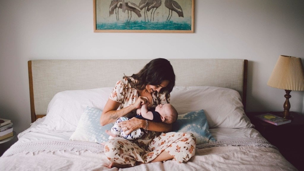 mom holding newborn baby on bed, fostering infant attachment