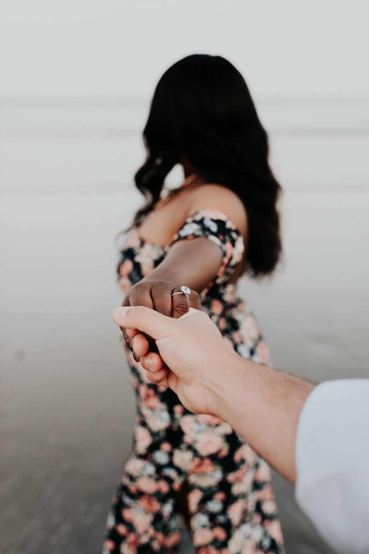 guy holding womans hand wearing an engagement ring