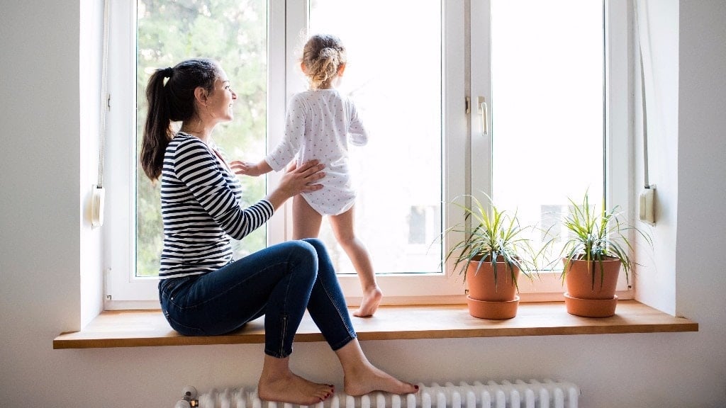 mom watching daughter play near a window