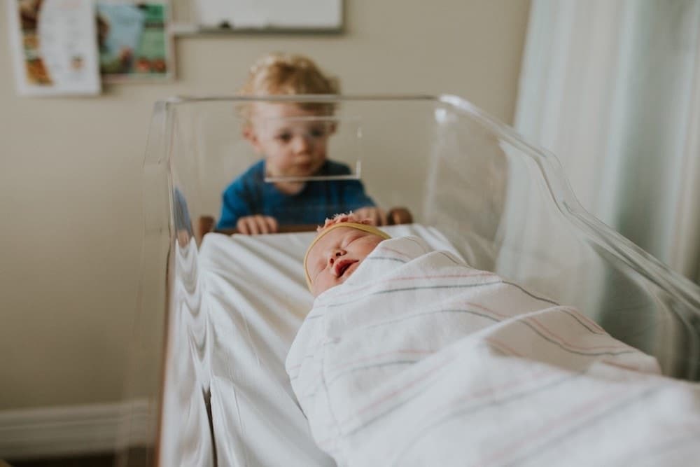 boy looking at newborn baby after an expensive birth