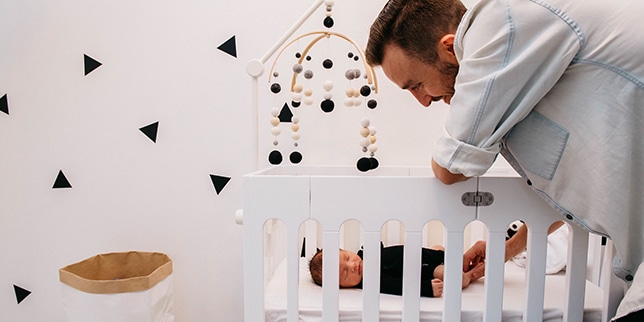 dad looking a sleeping baby in crib