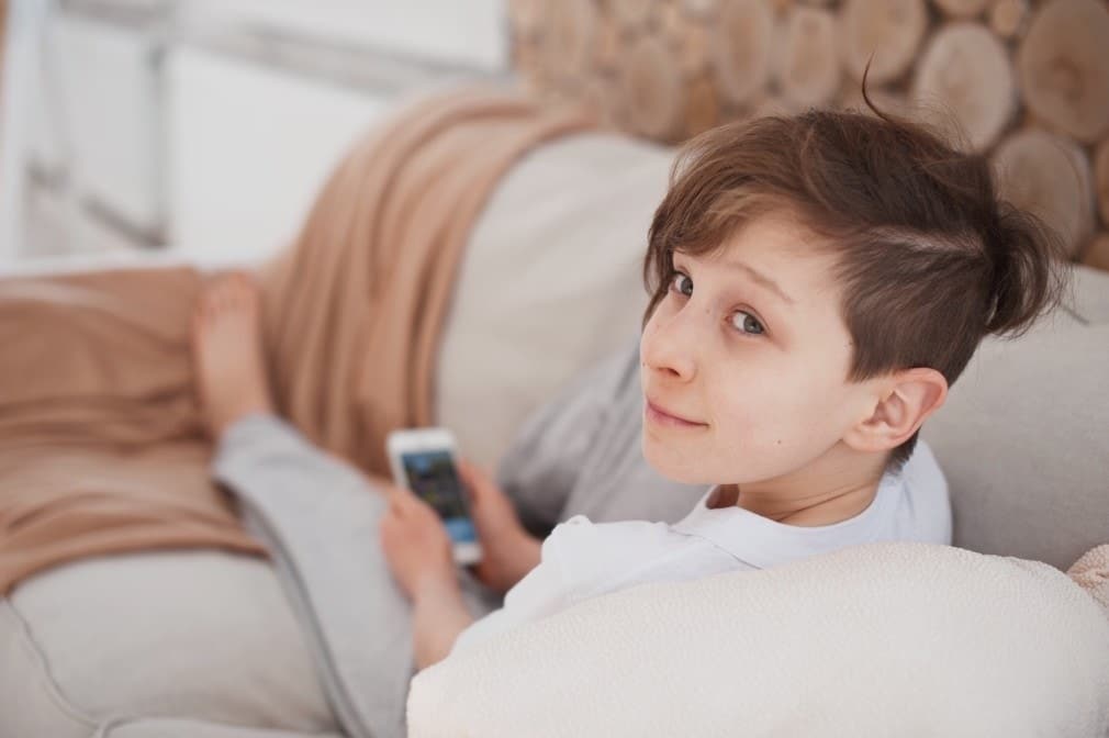 tween sitting on couch with phone