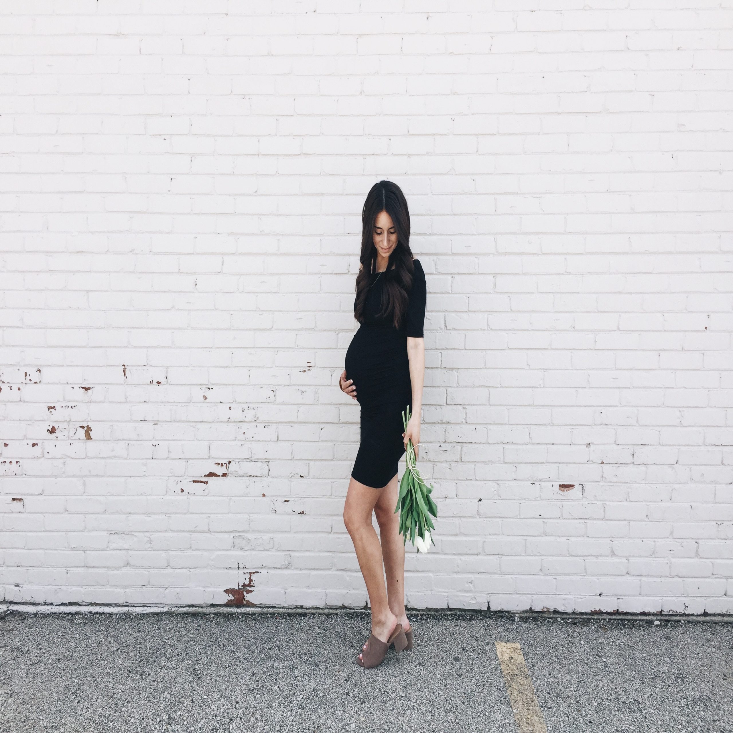 pregnant woman holding belly in front of a brick wall