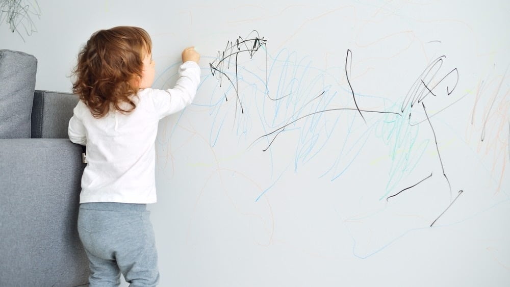 little girl drawing on the wall