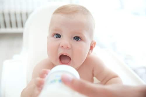 baby reaching for a bottle- don't ask about breastfeeding