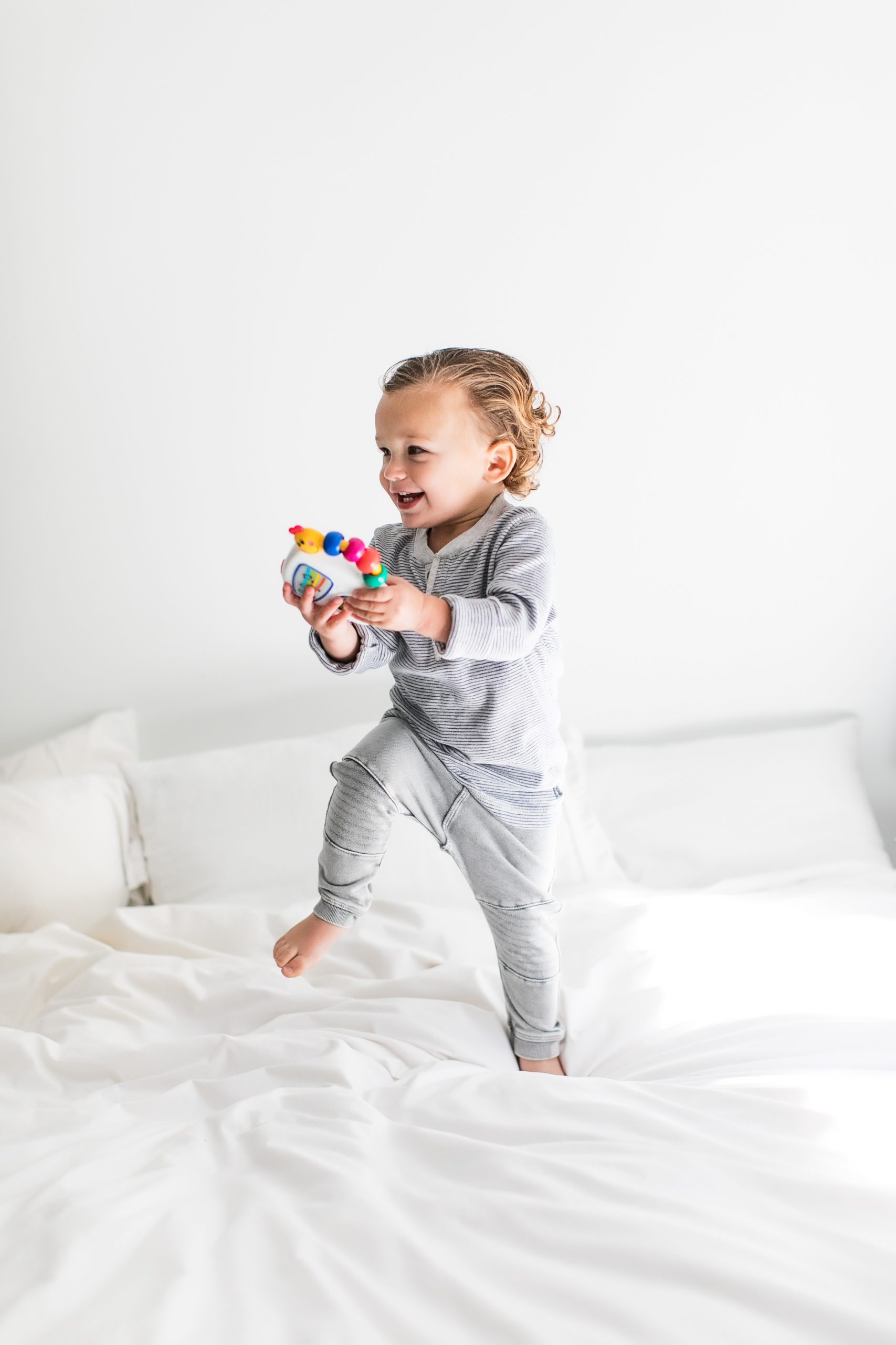 baby holding rattle toy and smiling