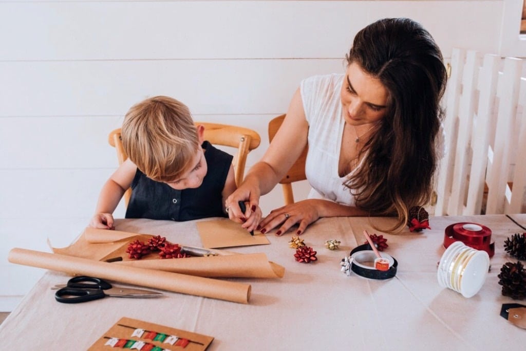 child helping mom write holiday cards- giving back to the community