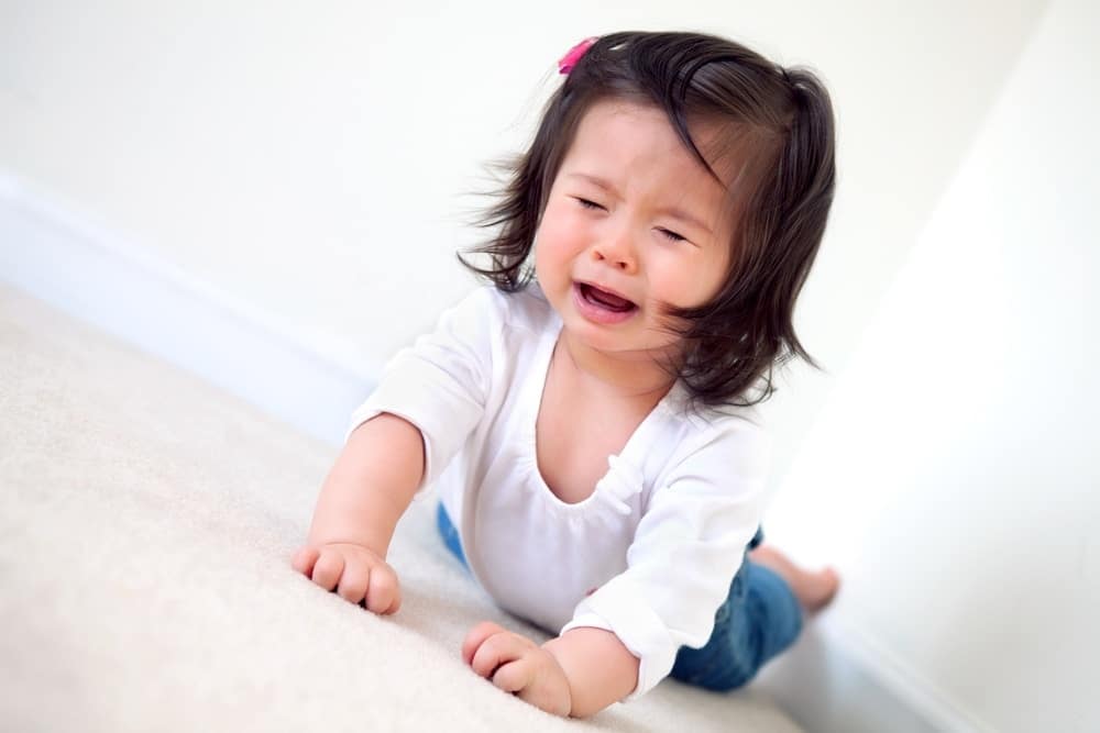 toddler girl crying while laying on floor