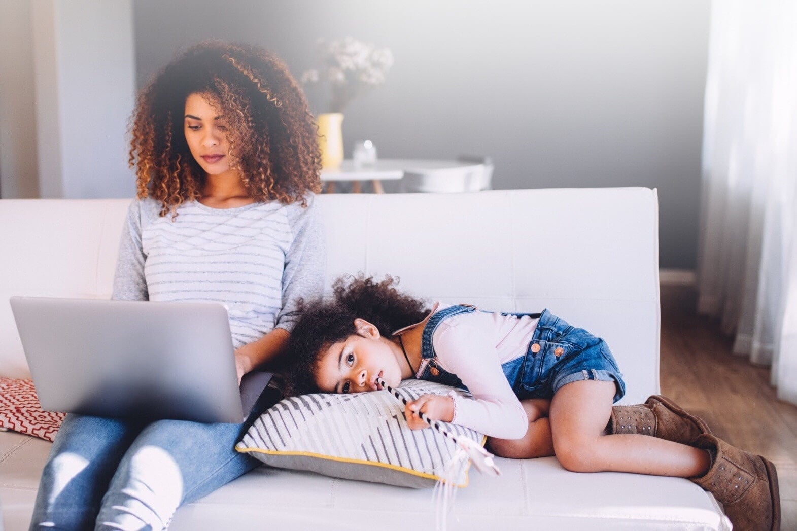 Child laying down next woman on laptop