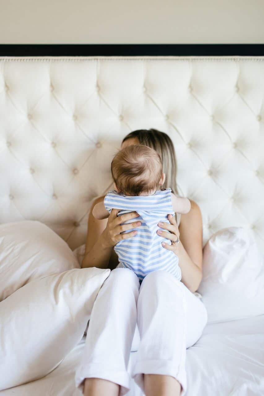 mom holding baby in bed