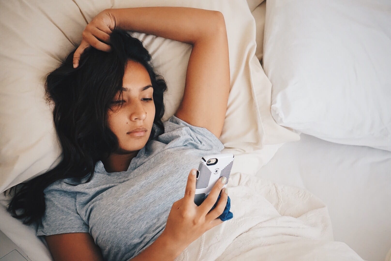 woman sitting in bed on her phone