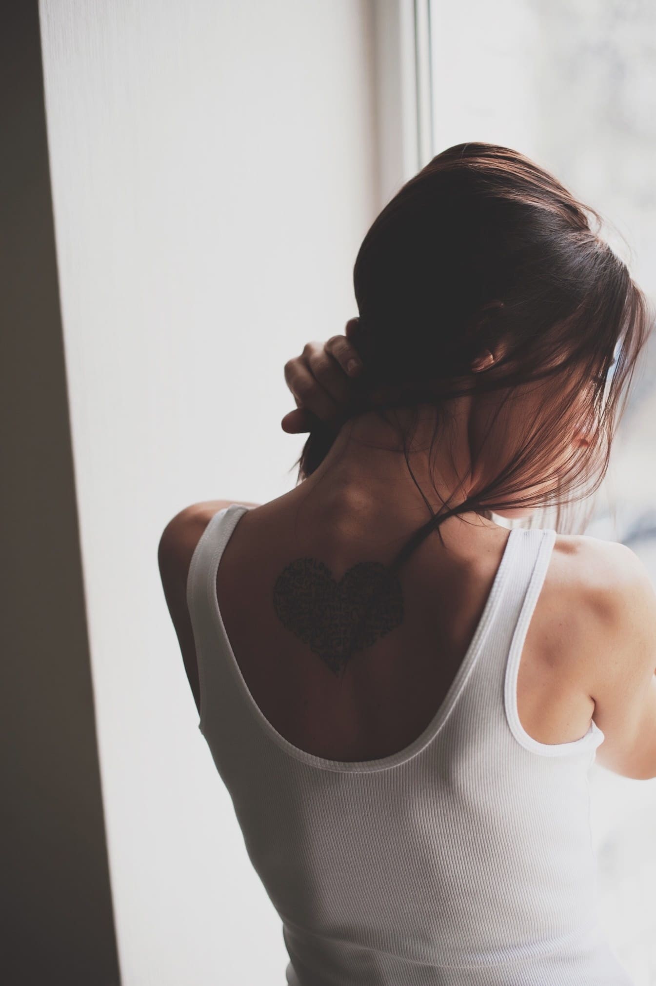 woman looking out the window with her hand on her neck