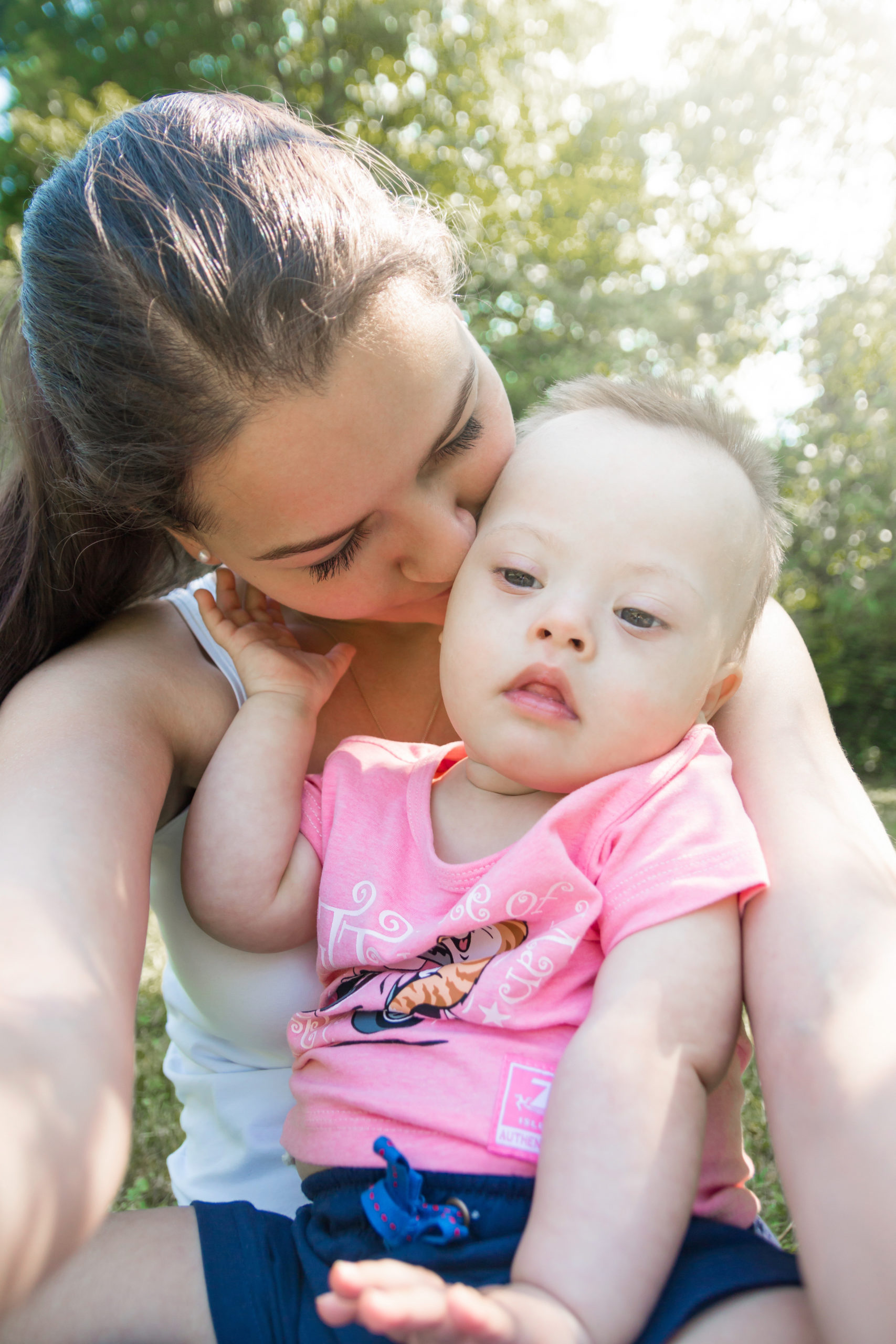 mom kissing her baby with Down Syndrome