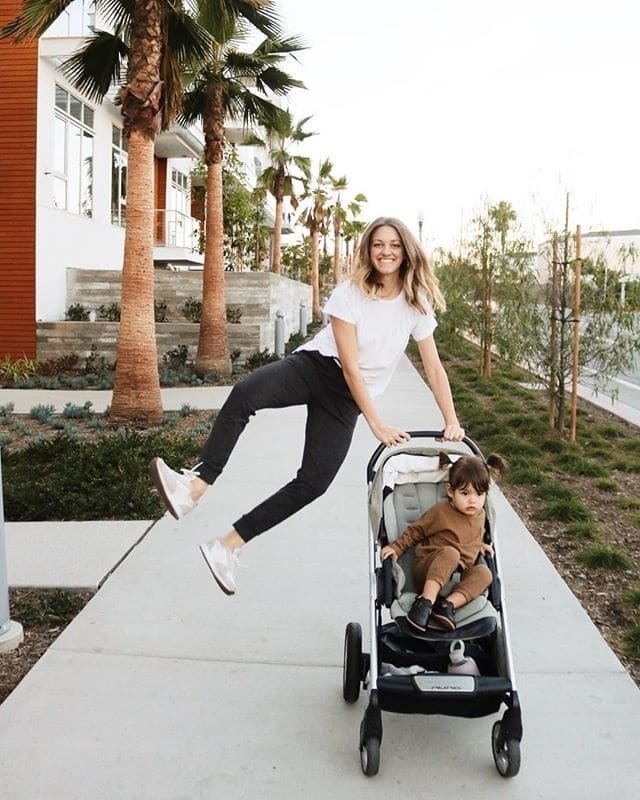 mother jumping beside her stroller, celebrating her mama milestones