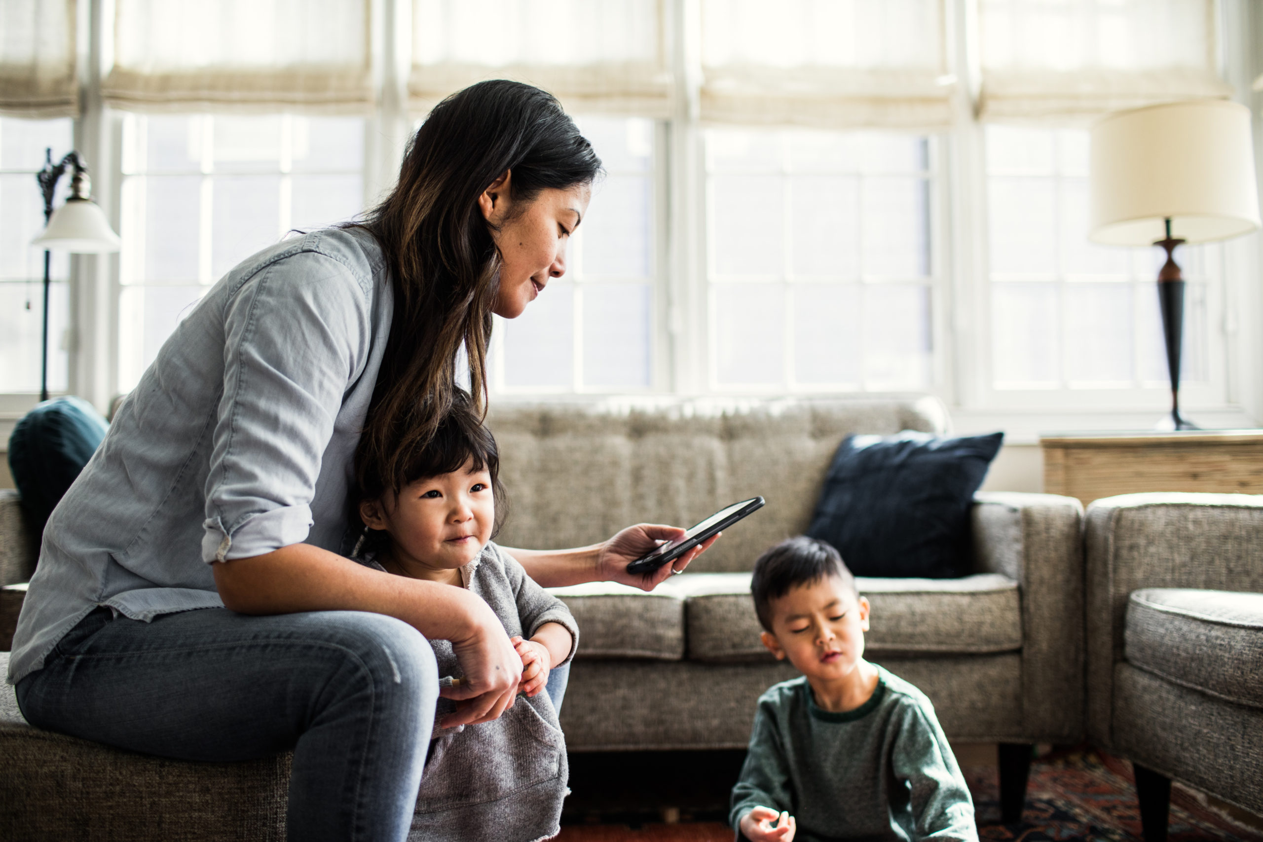 mom sitting on couch with two kids next to her- invisible labor