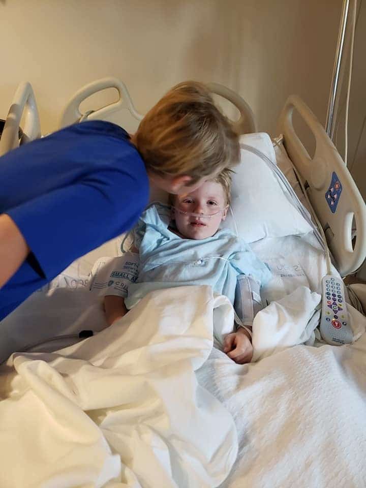 mom kissing son in a hospital bed on his head