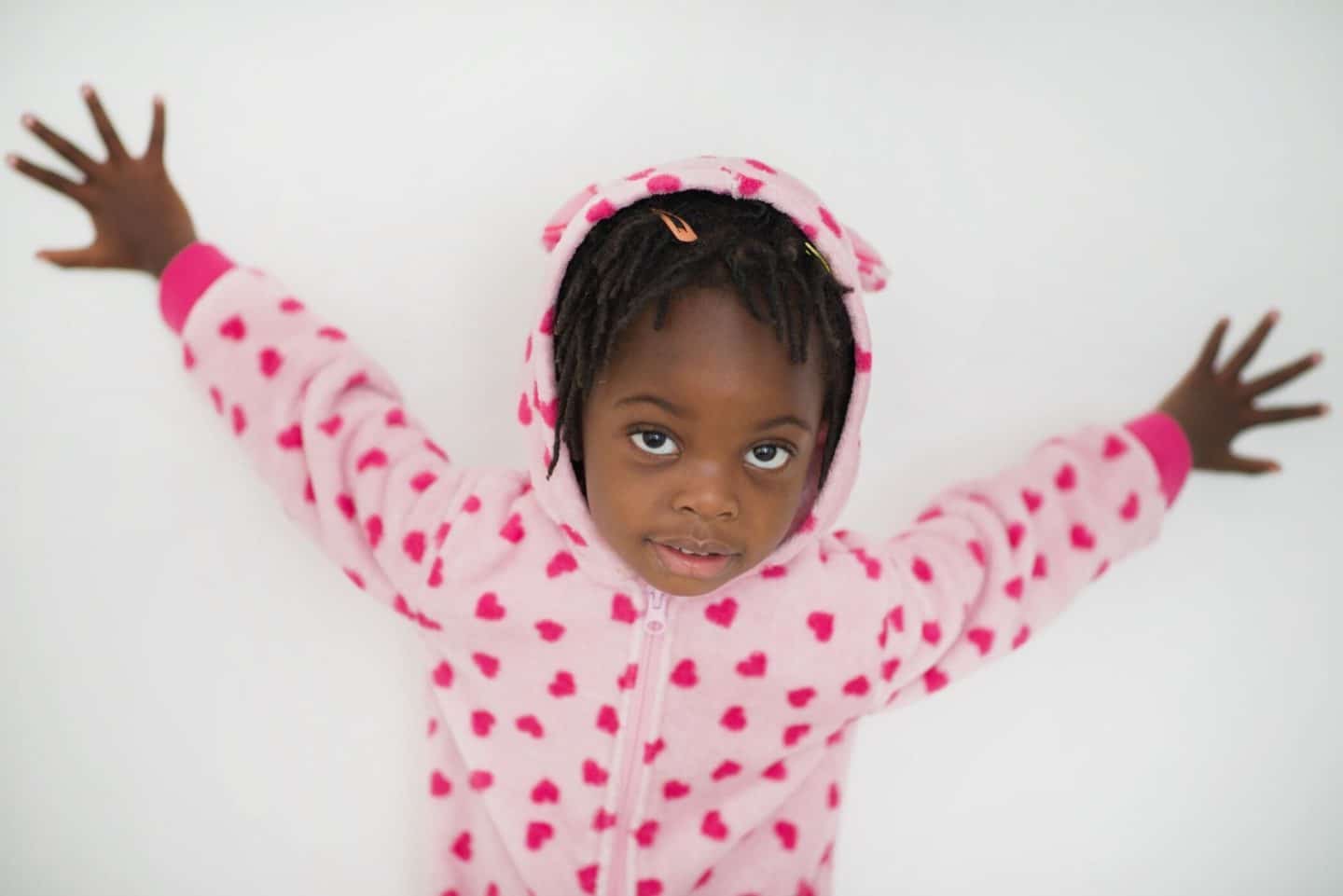 little girl opening up her arms and looking at the camera