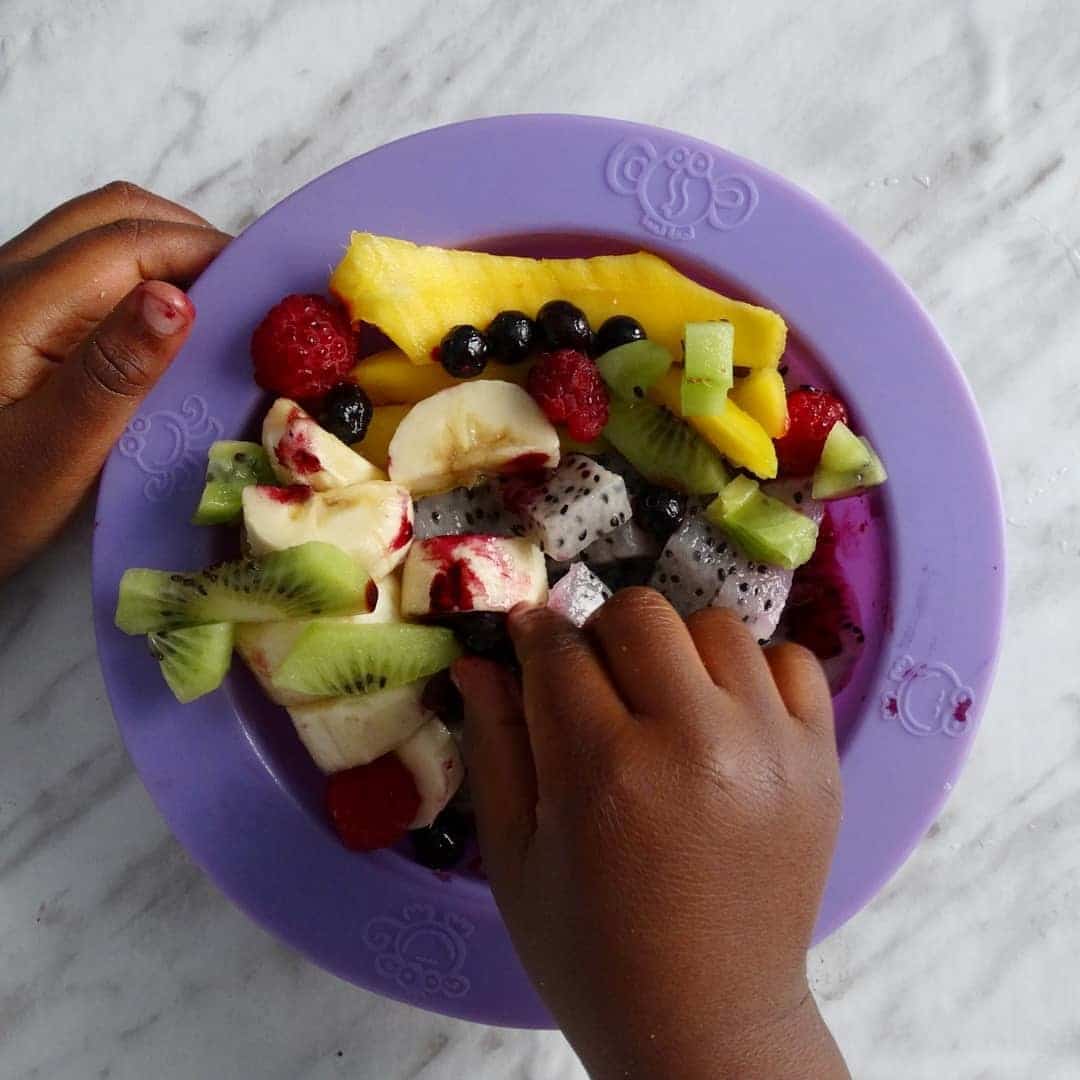 little kid eating a bowl of fruit