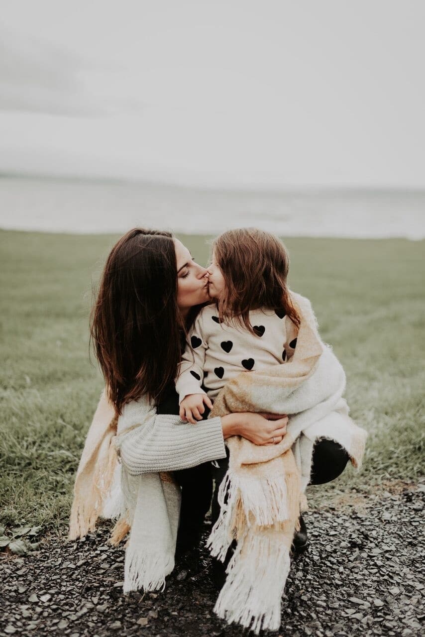 mom kissing daughter on first day of kindergarten