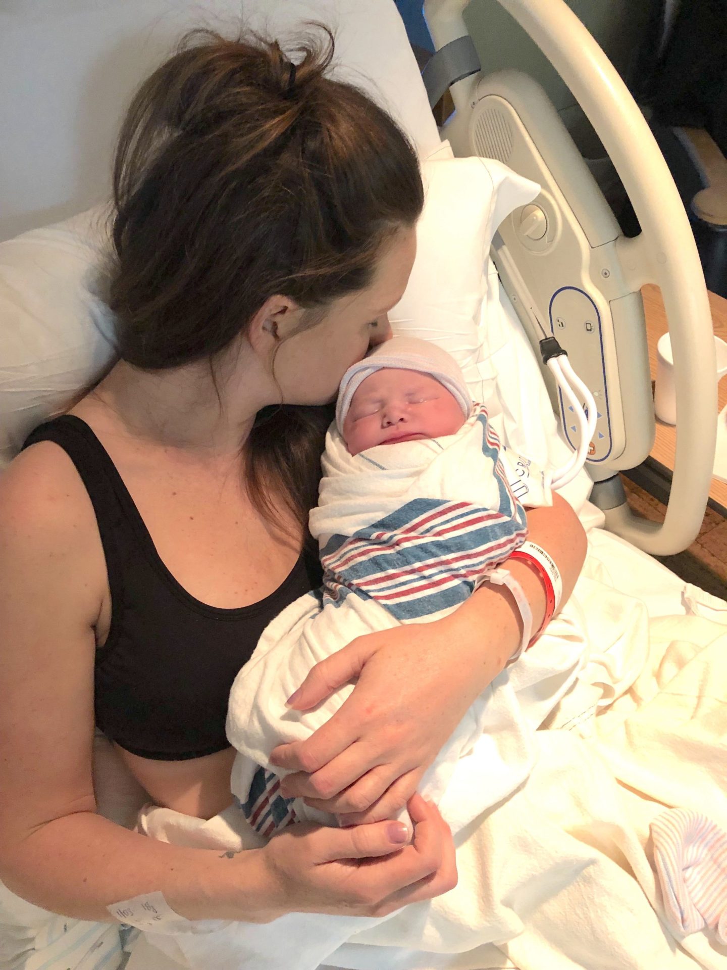 mom kissing newborn baby in the hospital