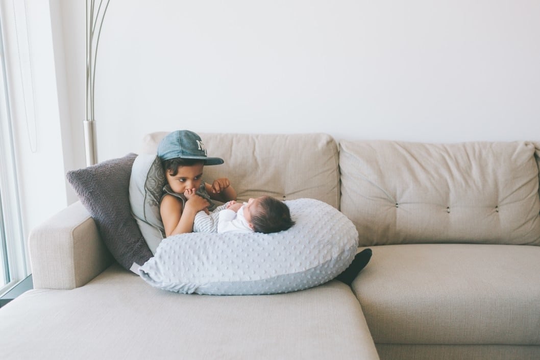 older sibling kissing newborn baby