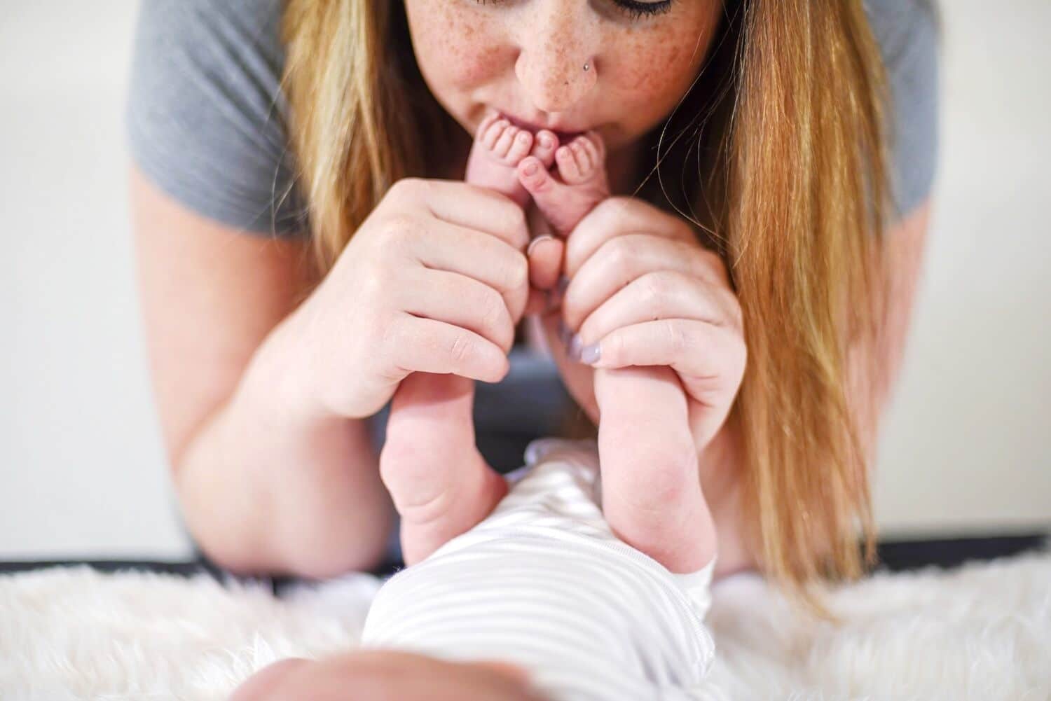 woman kissing baby's feet