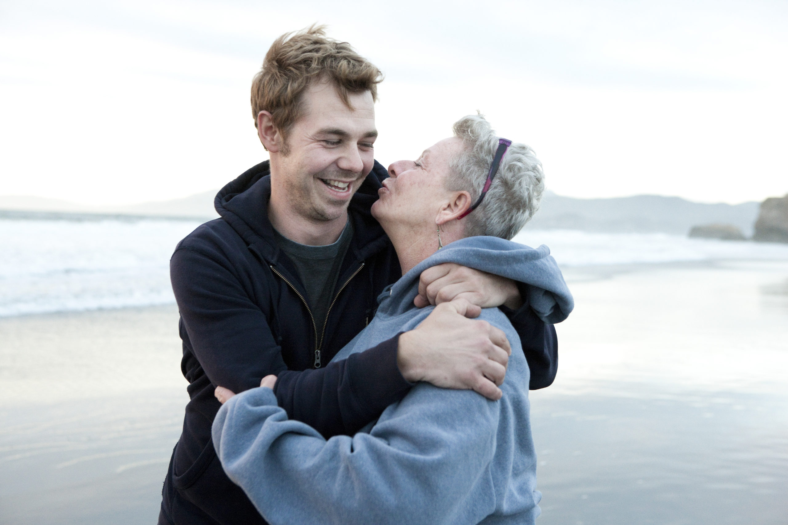 mother hugging son on the beach and leaning in to kiss his cheek- thank you letter to mom